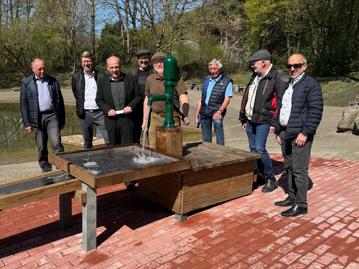 So fließt das Wasser: Tierparkleiter Stefan Heffels bringt die Pumpe des neuen Wasserspielplatzes im Beisein von Vorstandsmitgliedern des Tierparkvereins und des Aufsichtsrates der Freizeitobjektegesellschaft in Schwung. Foto: Stadt Alsdorf