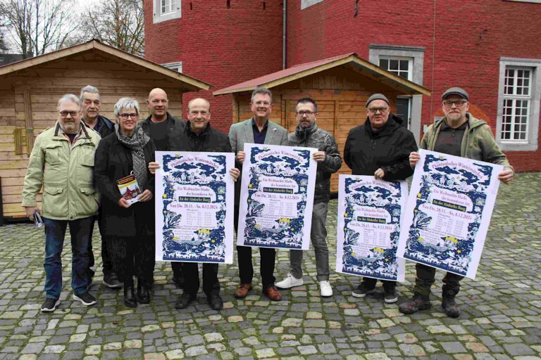 Die Buden stehen bereit: Neben Bürgermeister Alfred Sonders (5.v.l.) freuen sich Detlef Loosz, Aufsichtsratsvorsitzender Stadtwerke Alsdorf GmbH, Nachtwächter Ludwig Grotenrath, Kathrin Koppe (Geschäftsführerin Stadtentwicklung Alsdorf GmbH), Martin Reckate, Ralf Kahlen (Geschäftsführer Stadtwerke), Mitorganisator Thomas Bongard sowie für die Aktionsgemeinschaft Stadtmarketing Alsdorf Kassierer Nijaz Ganic und Vorsitzender und Marktleiter Stefan Heffels (von links) auf das „Phantastische Wintermärchen“. Foto: Stadt Alsdorf